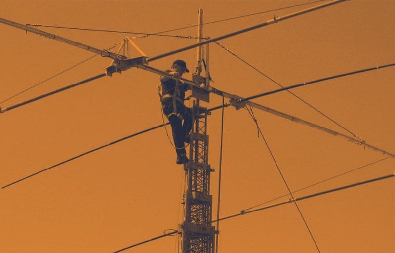 Image of a service operator atop an antenna making adjustments